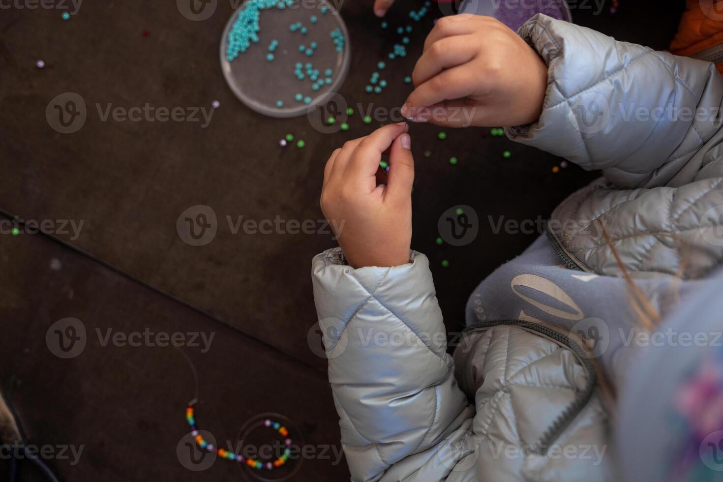 little children's hands weave a bead bracelet close-up shot photo