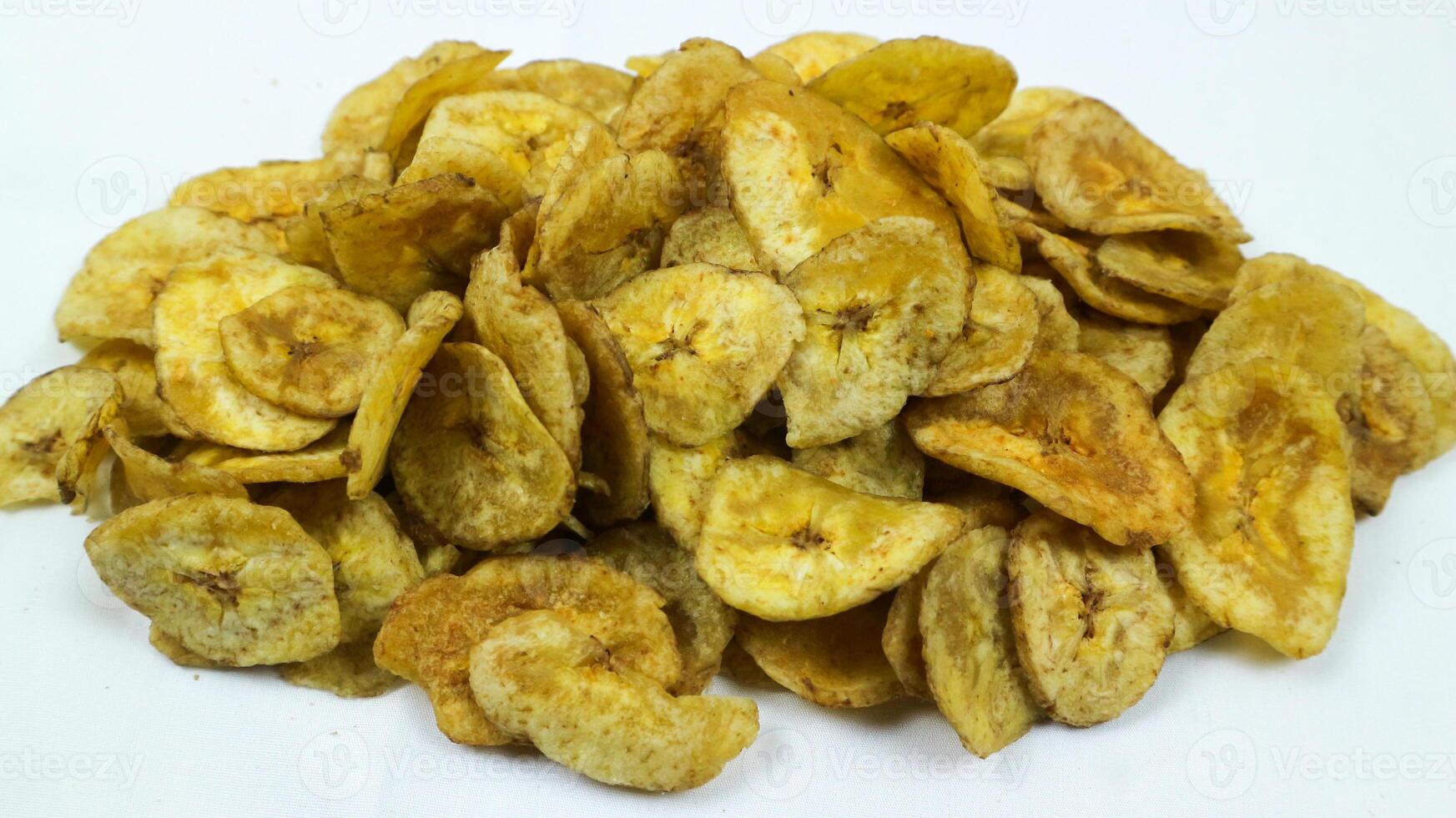 A bowl of sweet banana fried chips or Keripik Pisang manis on a square pattern napkin and white background. Popular indonesian traditional snack. Selective Focus. photo