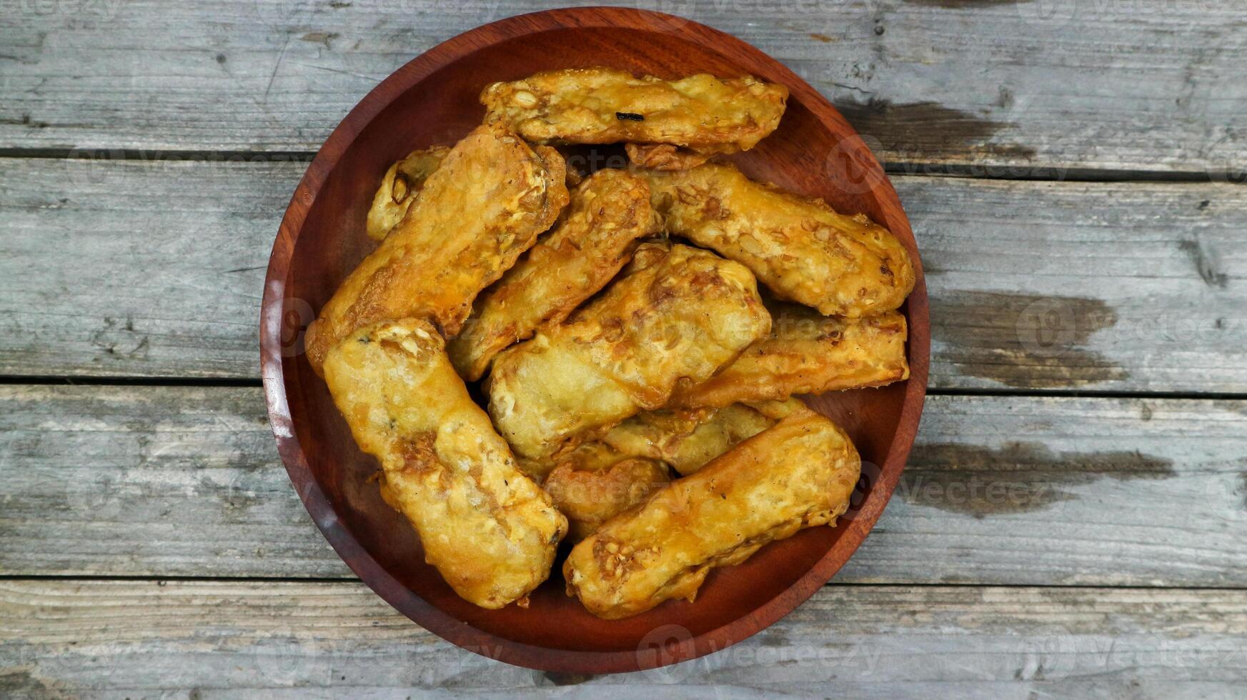 Indonesian traditional meal named tempe goreng. fried fermented soybean cake served in a wooden plate photo