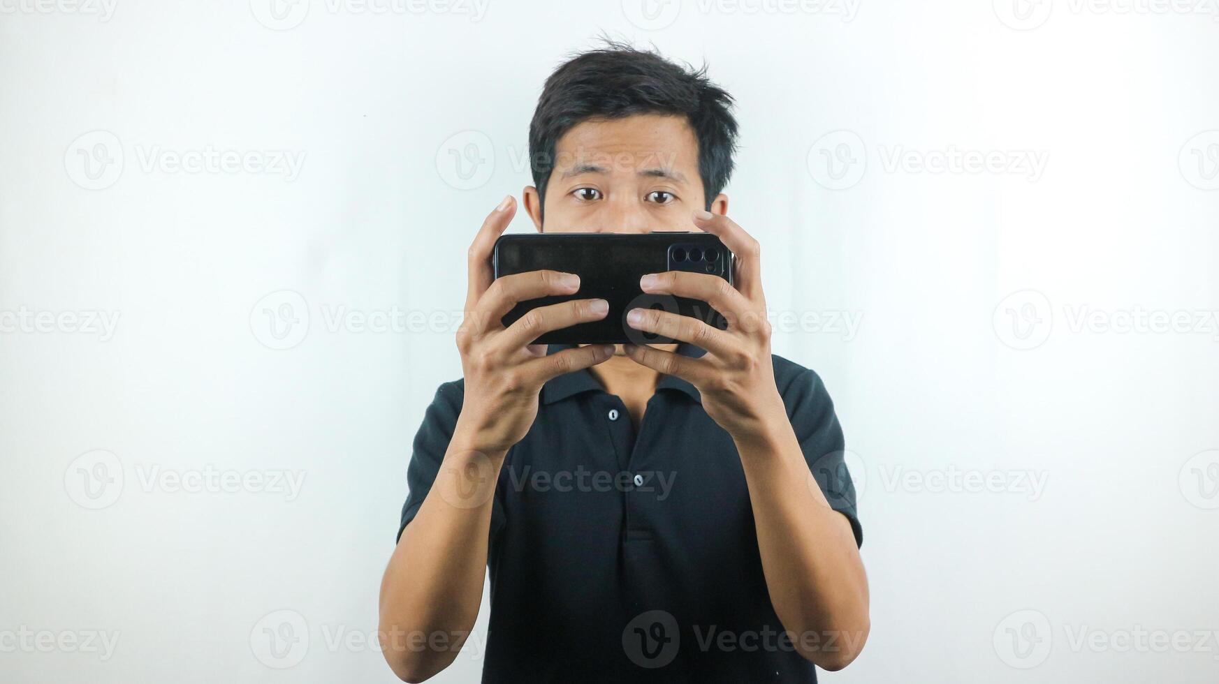 Asian man with a serious expression is playing a game on his cell phone. photo