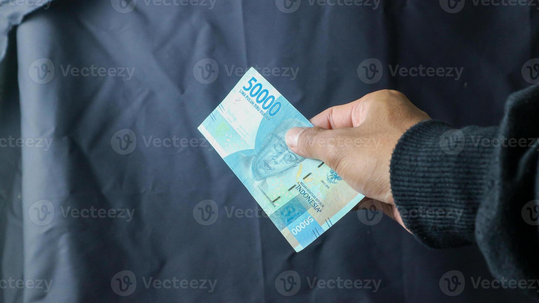 Asian young woman in black coat transacting rupiah with men only the hands, transaction concept, financial concept. asian man holding rupiah banknotes, isolated on black and white background. photo