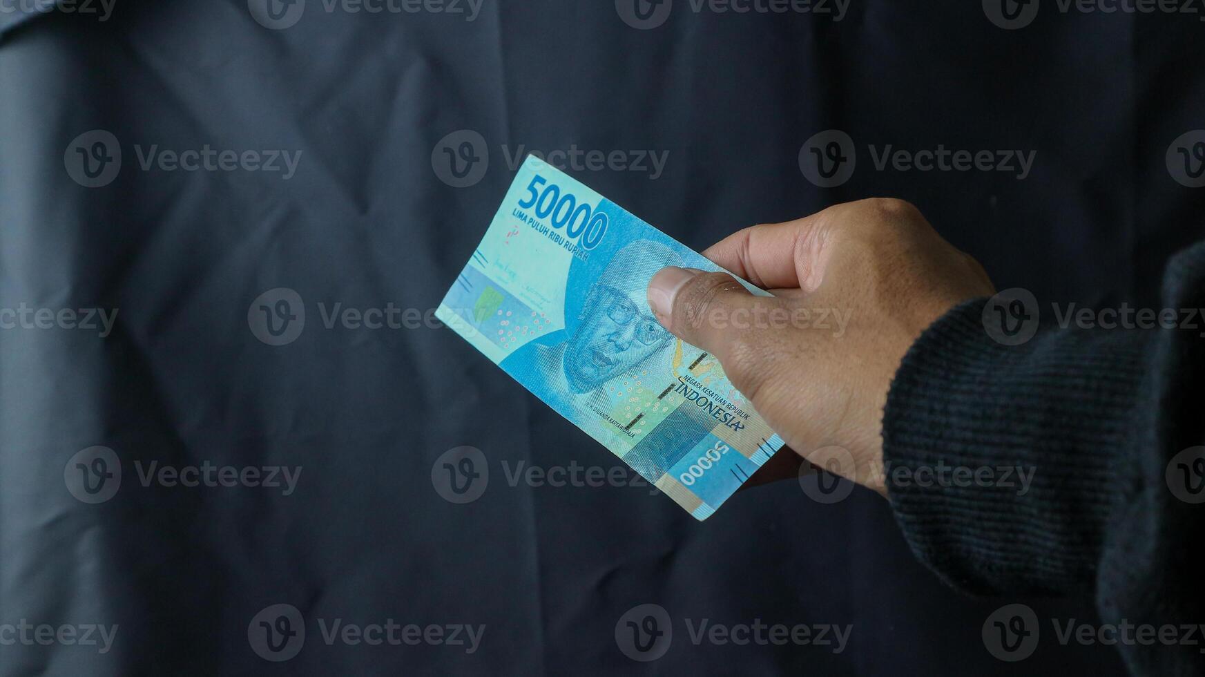 Asian young woman in black coat transacting rupiah with men only the hands, transaction concept, financial concept. asian man holding rupiah banknotes, isolated on black and white background. photo