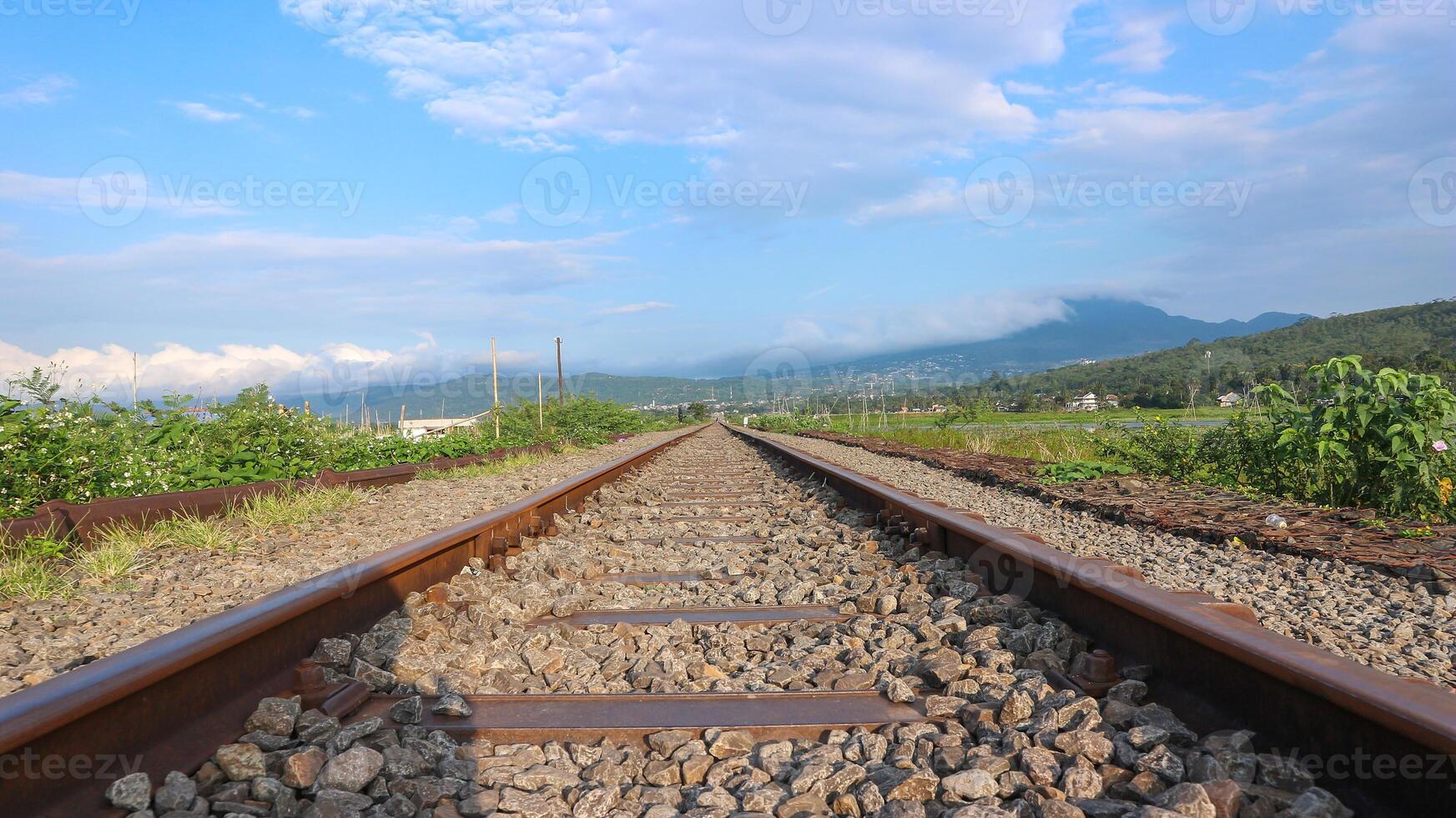 Railroad track in sunny clouds. The railway passes through the autumn forest. photo