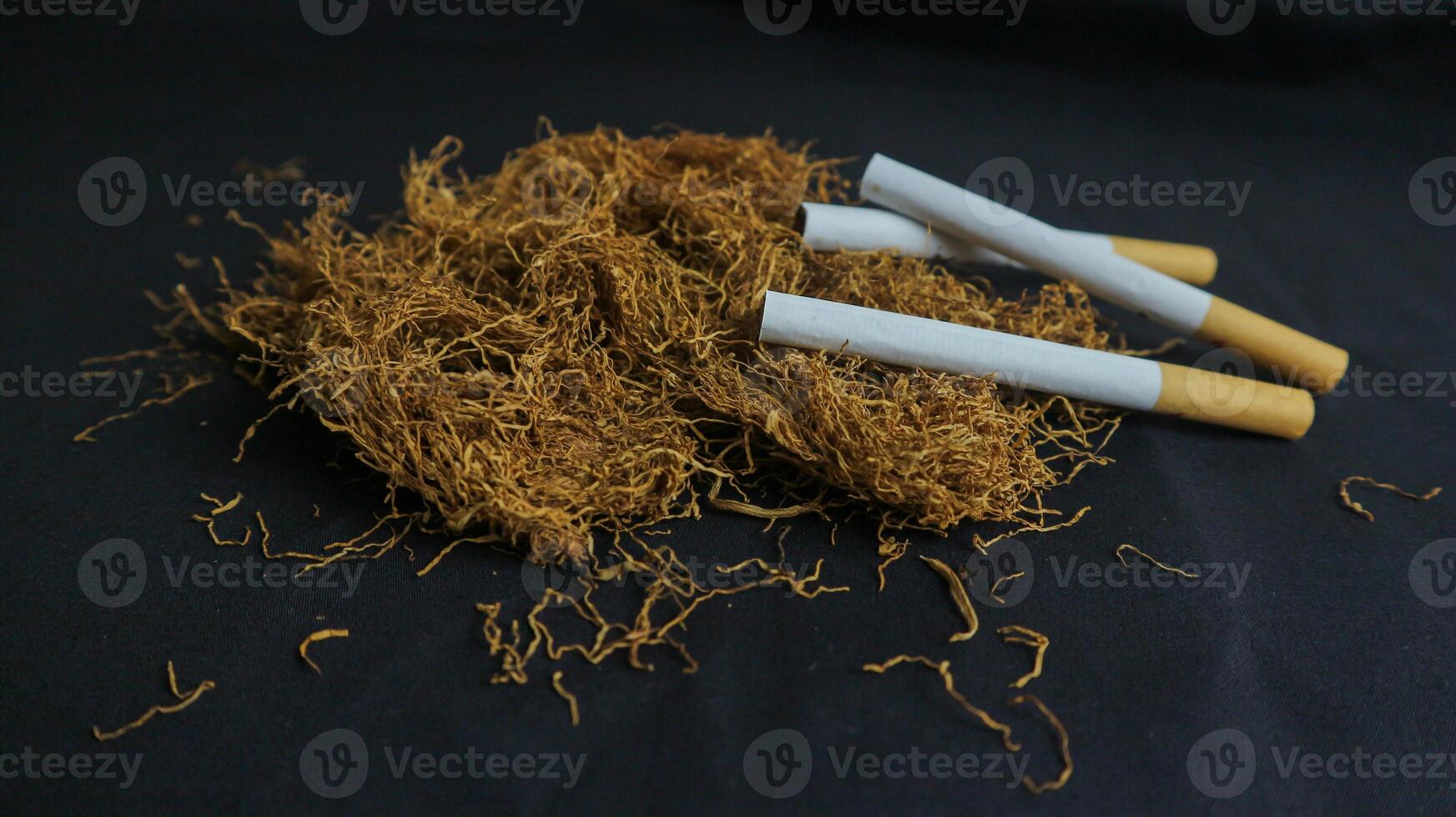 cut tobacco leaves and handmade cigarettes on black background photo
