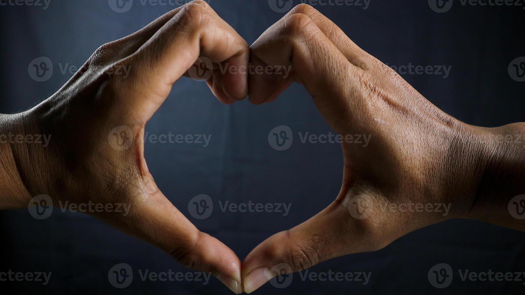 Hands in heart shape, interracial friendship isolated on black background. photo