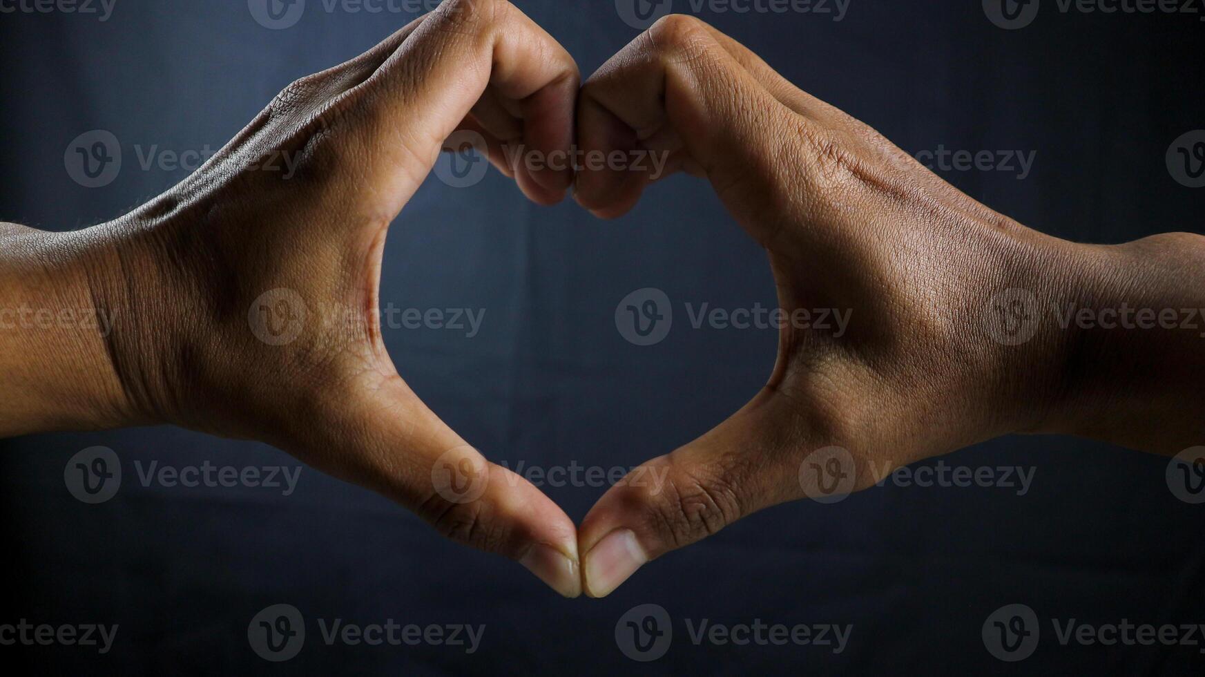 Hands in heart shape, interracial friendship isolated on black background. photo