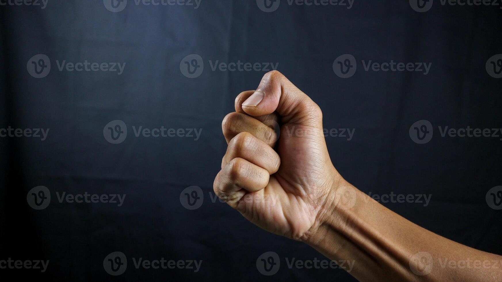 Counting, aggression, brave concept. Black male fist, clenched hand, strong male man raised fist power, protest, fist ready to fight isolated on black background. photo