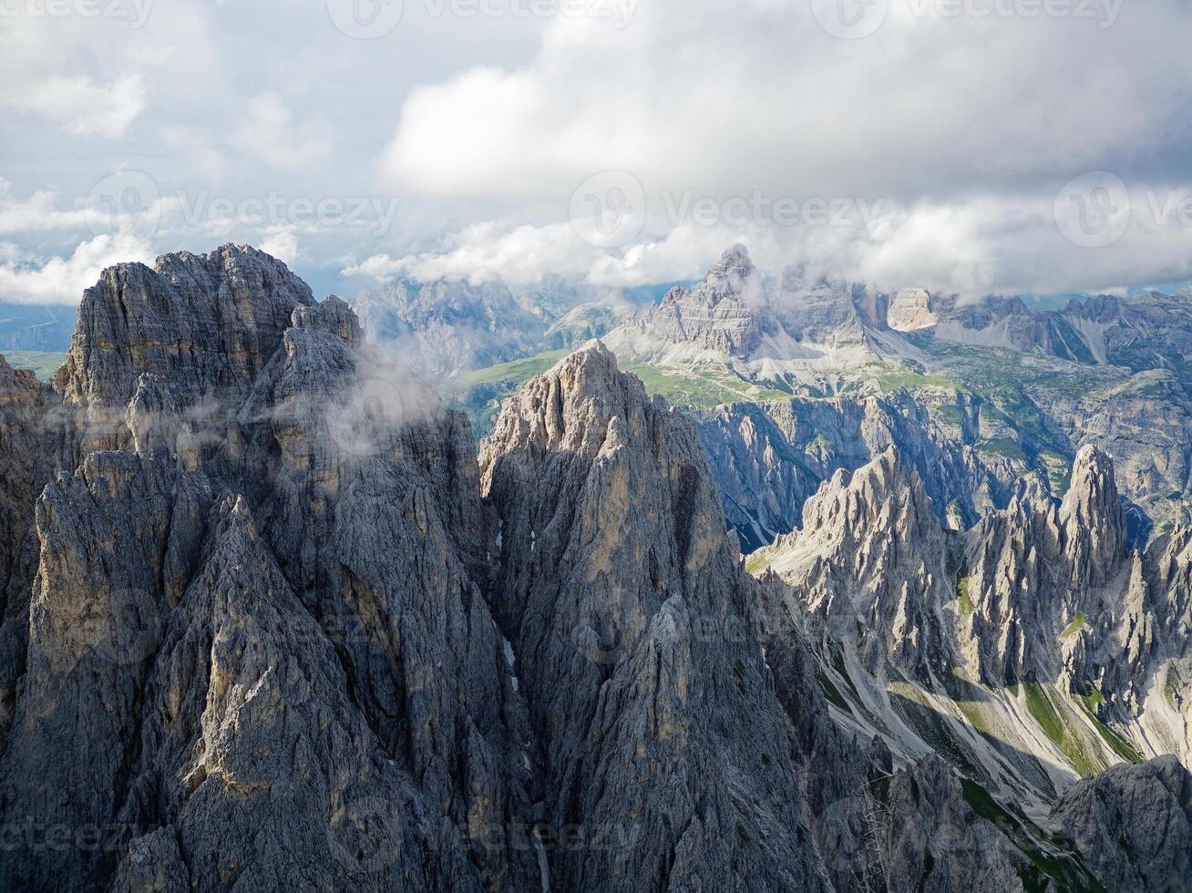 Aerial view of Cadini di Misurina mountains with Tre Cime di Lavaredo mountains in the background during a sunny day with some clouds. Dolomites, Italy. Dramatic and cinematic landscape. photo