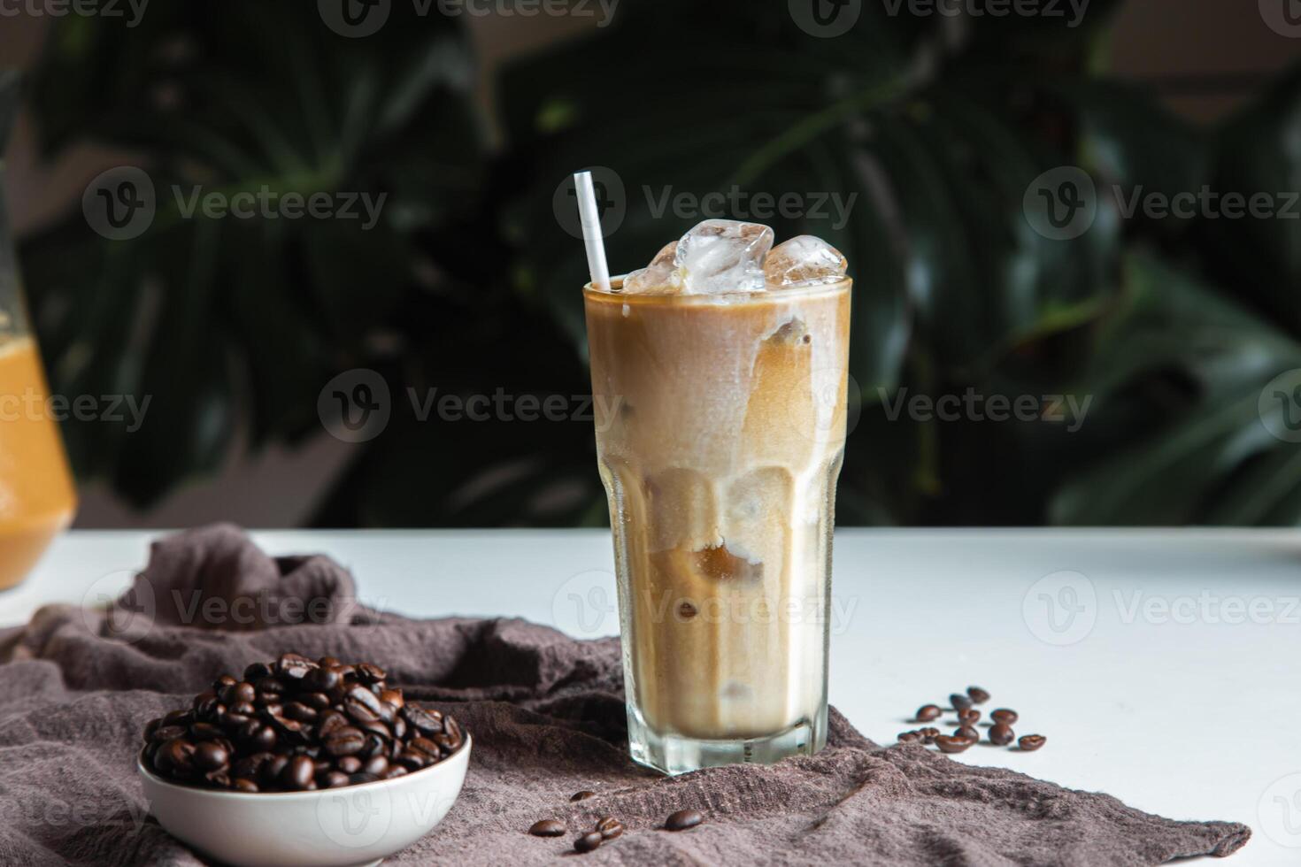 Iced of coffee cup on glass cup and beans coffee place on white table copy space foryour text. photo