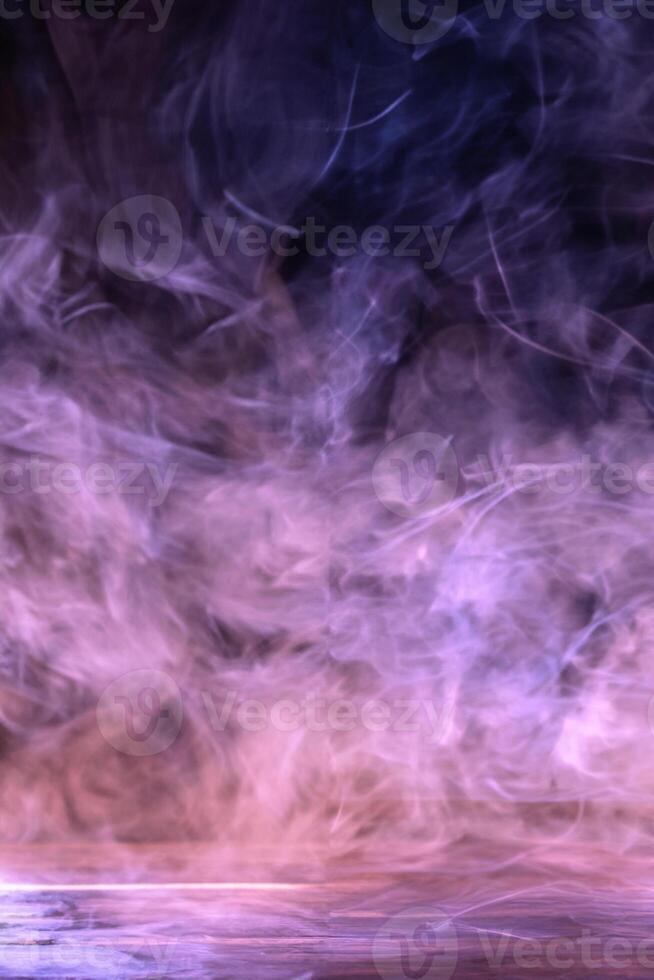 Conceptual image of multi-colored smoke isolated on dark black background and wooden table. photo