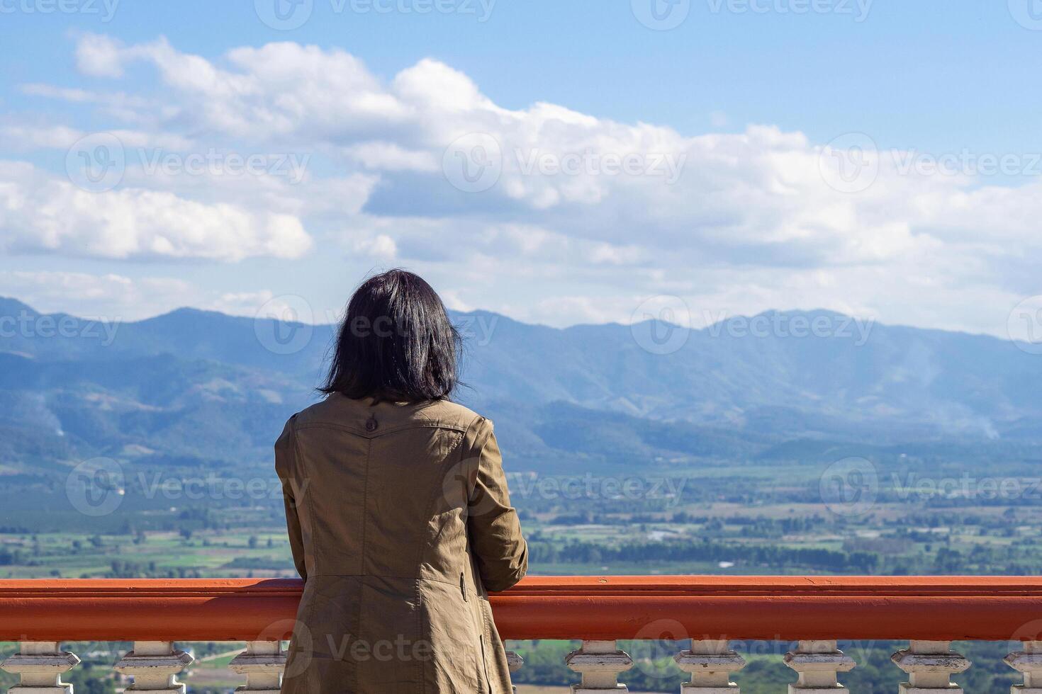A back view of a middle woman stands alone looking at mountains. Beautiful nature background. Concept of people and relaxation photo
