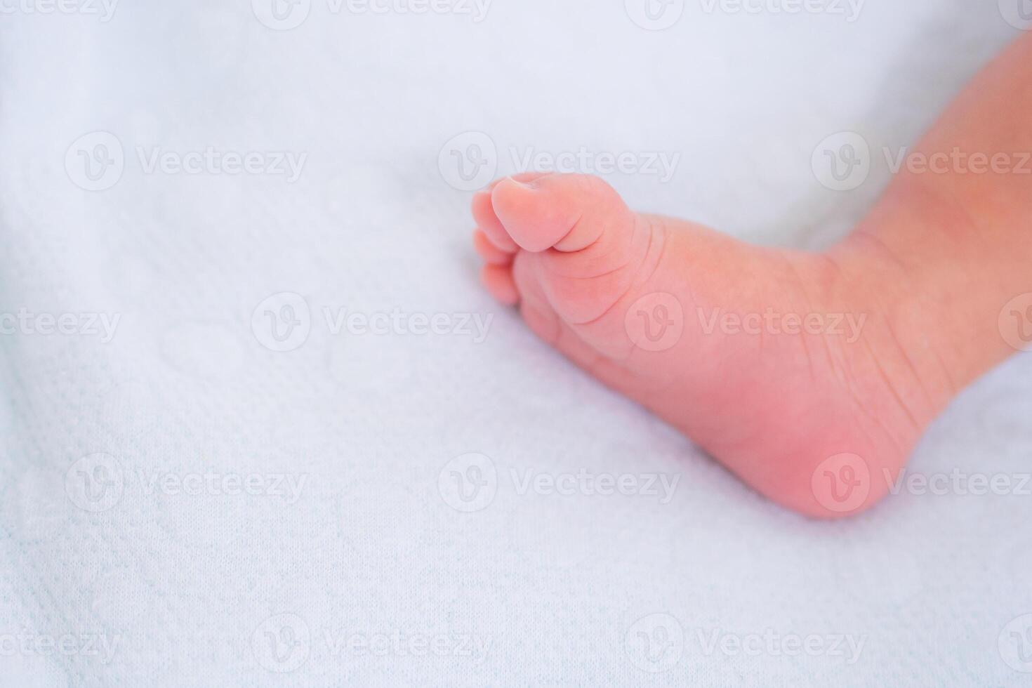 Little foot of newborn baby on a white blanket with copy space for your text. Selective focus. Love of family concept photo