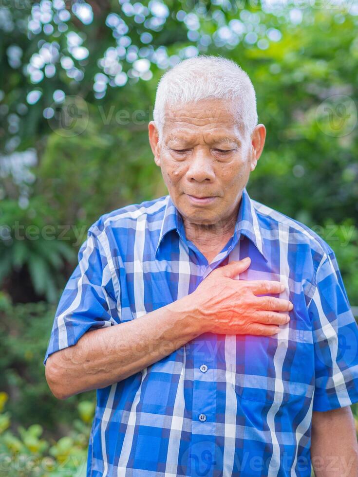 mayor hombre teniendo un corazón ataque. mayor asiático hombre agarrando su cofre en dolor a el primero señales de . concepto de Envejecido personas y cuidado de la salud foto