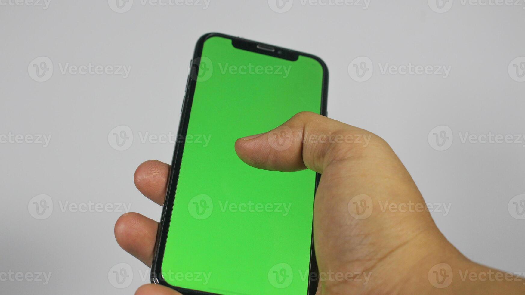 Hand holding smart phone with green screen. Isolated on white background photo