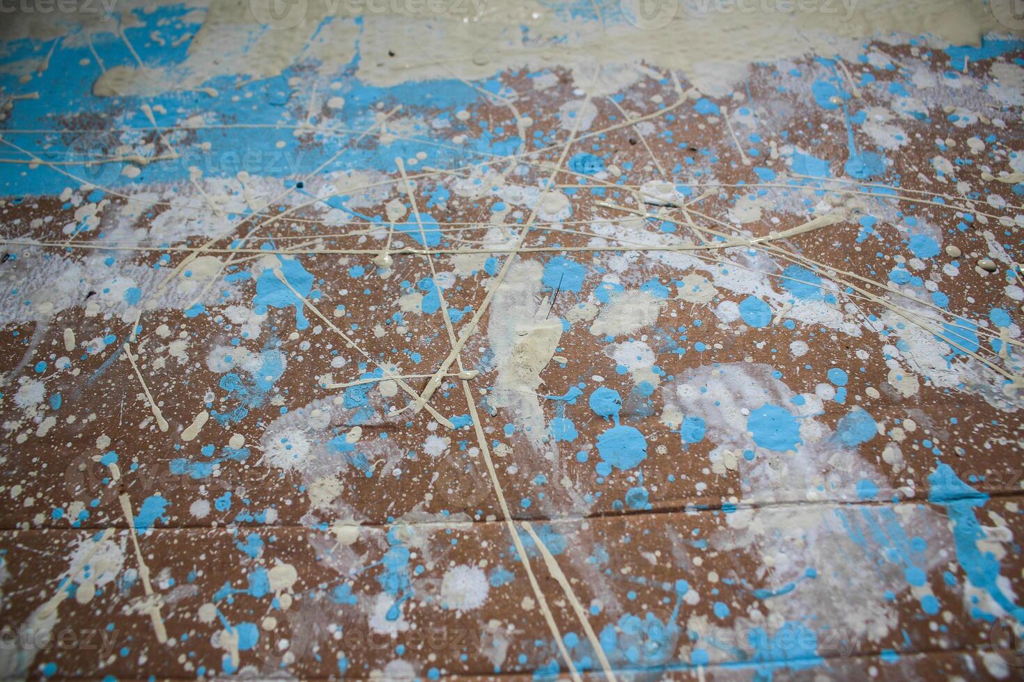 Abstract spots, drops of yellow blue white paint on a brown wooden surface photo