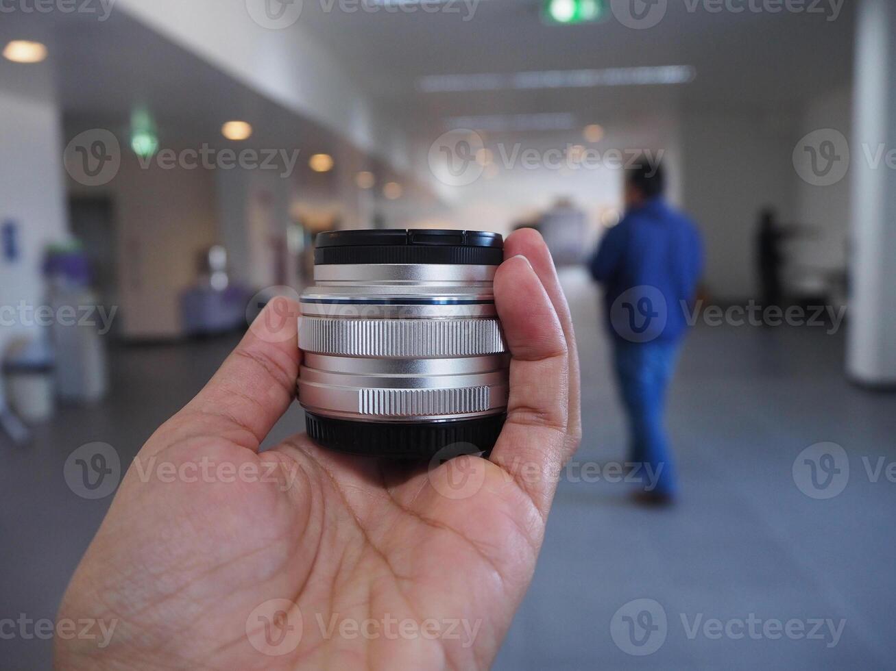 Close-up of a woman hand holding camera lens while standing in the office photo