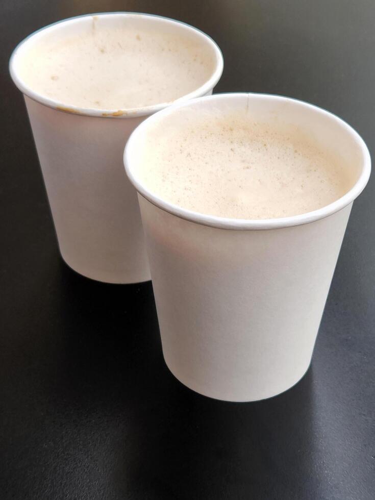 Two cups of coffee. Two paper glasses with coffee on a black background photo