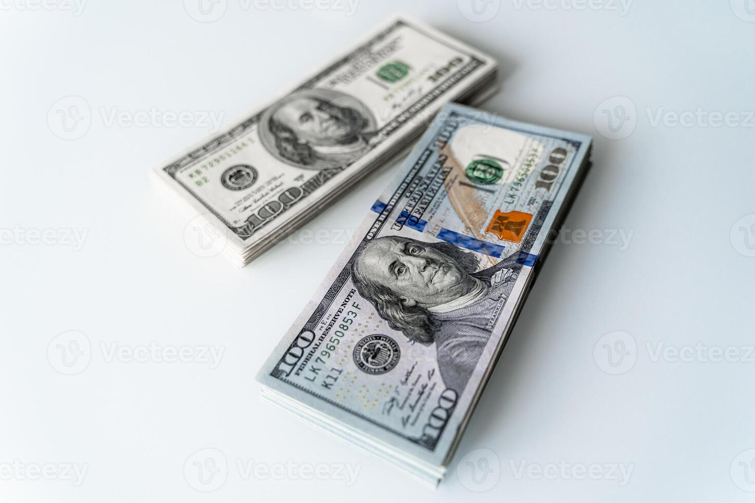 Stacks of One Hundred Dollar Bills on a White Surface. Two stacks of one hundred dollar bills on a white surface photo