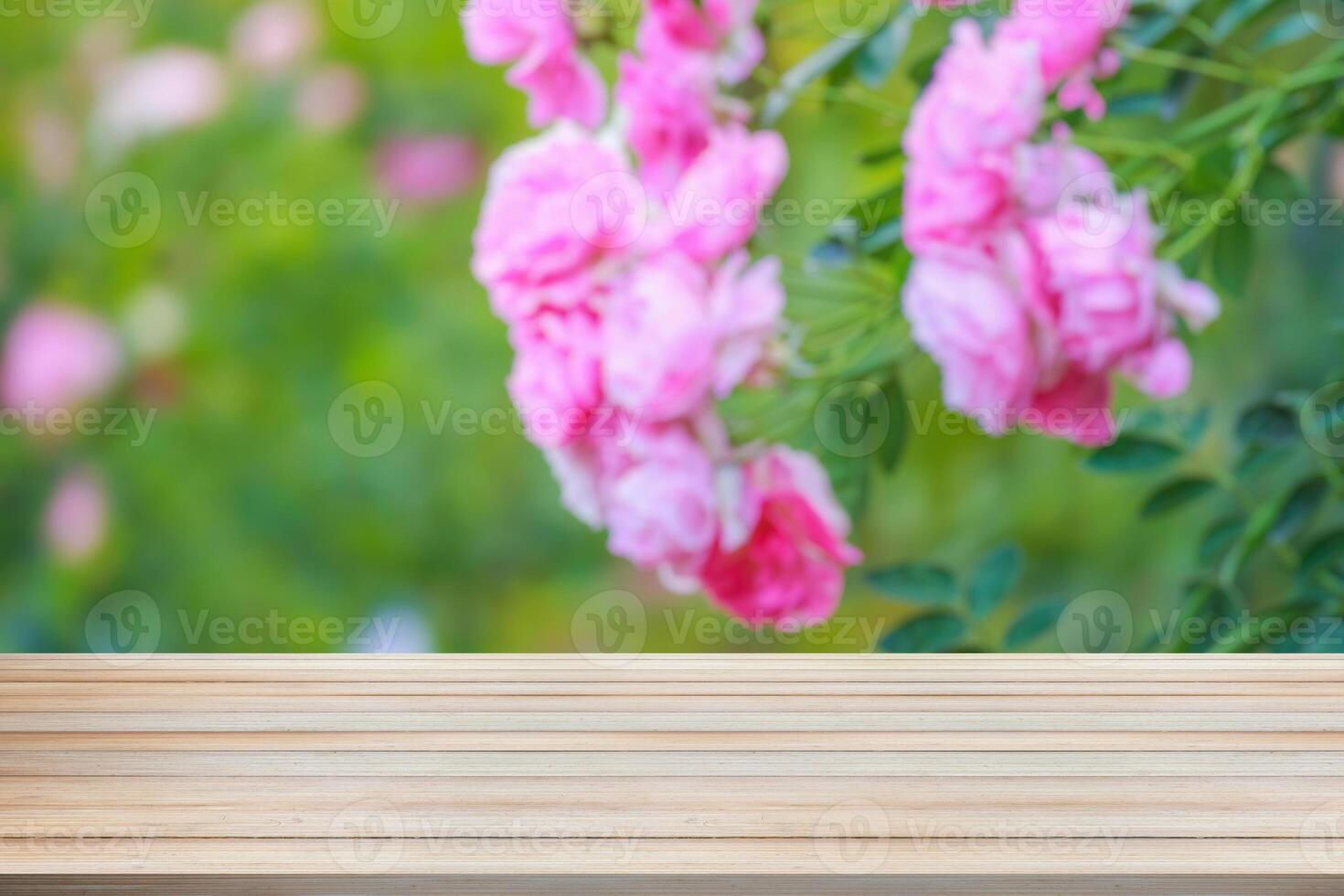 Empty wood table top with blur rose garden background for product display photo