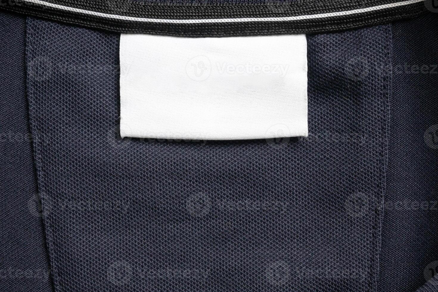 Blank white laundry care clothes label on black shirt fabric texture background photo