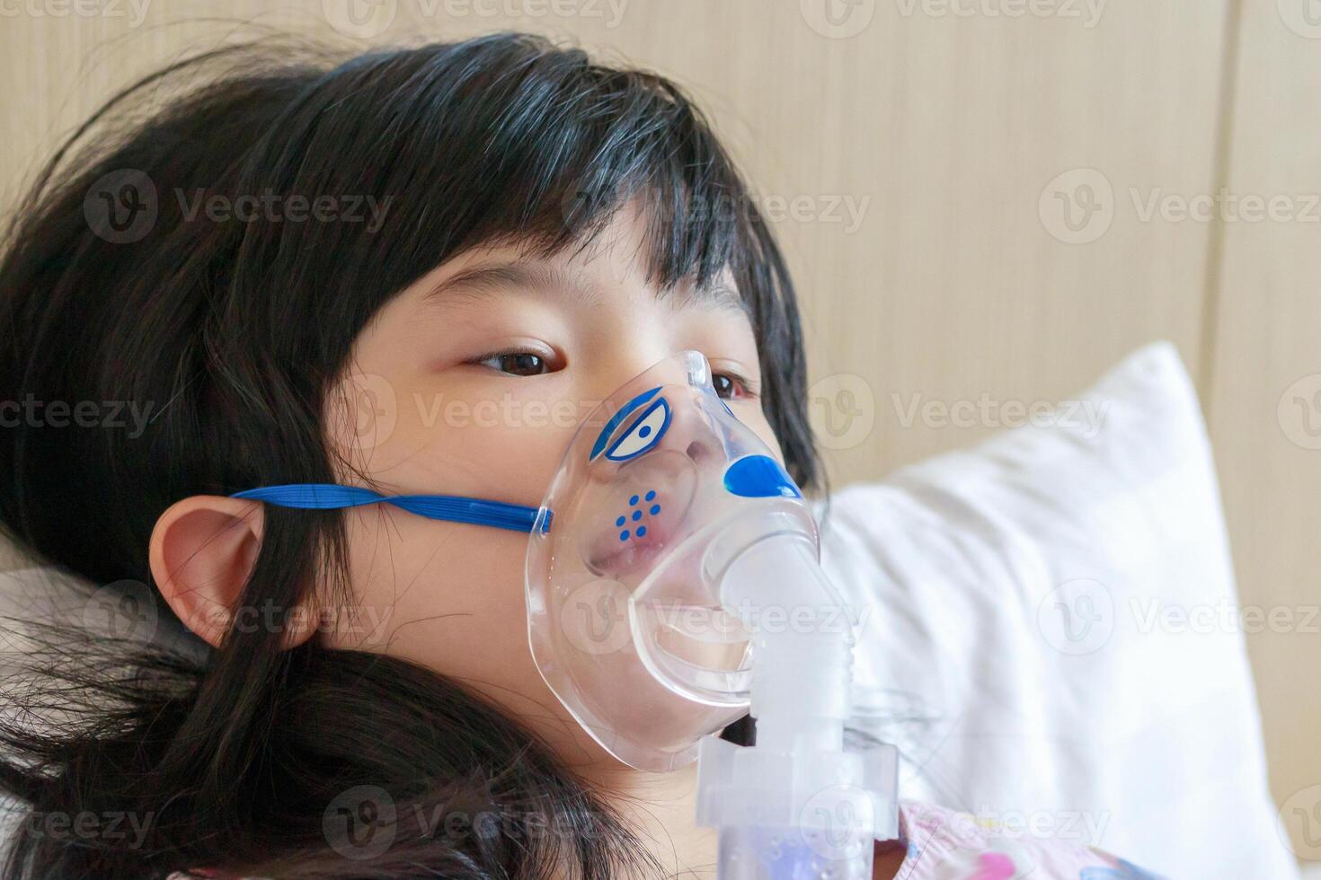 Sick little asian girl inhalation with nebulizer for respiratory treatment photo