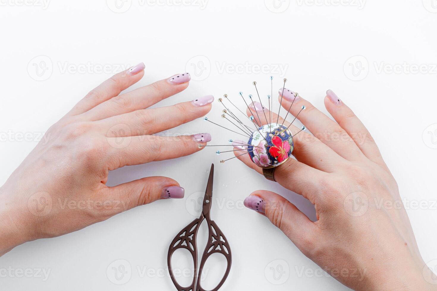 un anillo con un pequeño almohada para agujas en un mano y tijeras en un blanco antecedentes foto