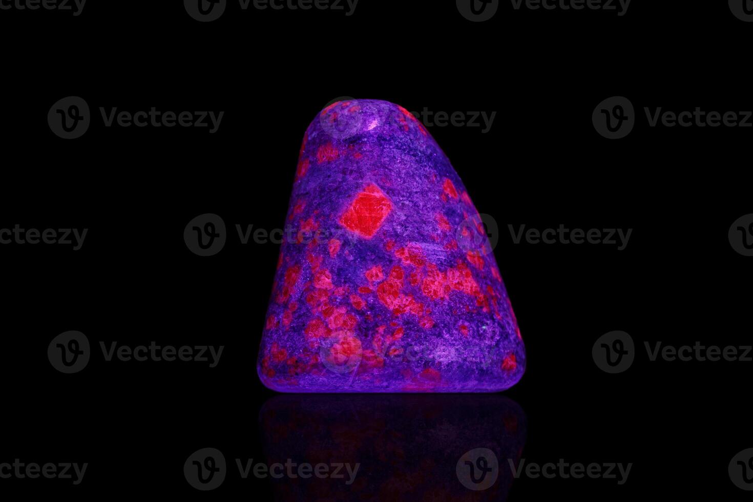 macro mineral stone ruby under ultraviolet light on a black background photo