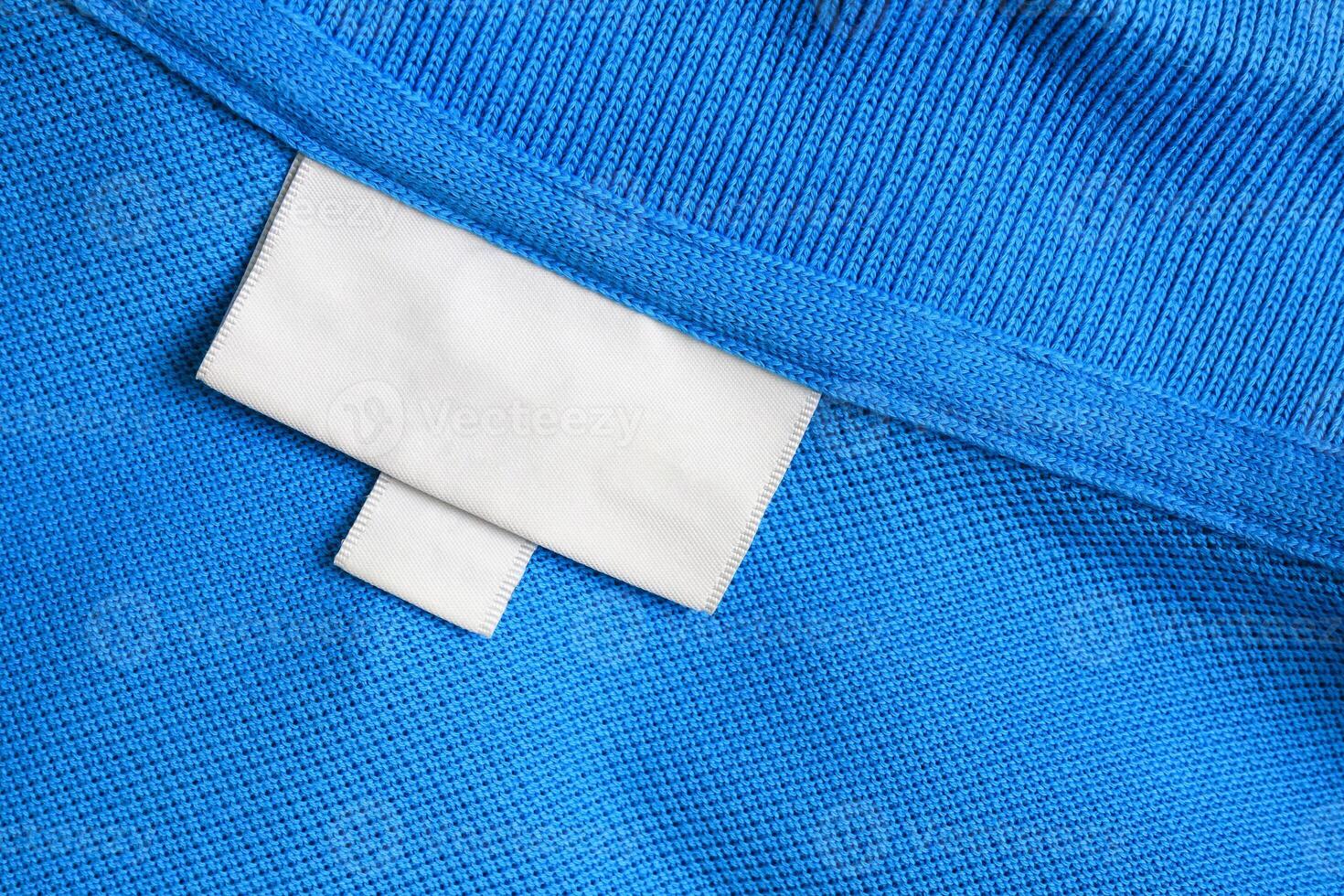 Blank white laundry care clothes label on blue shirt fabric texture background photo