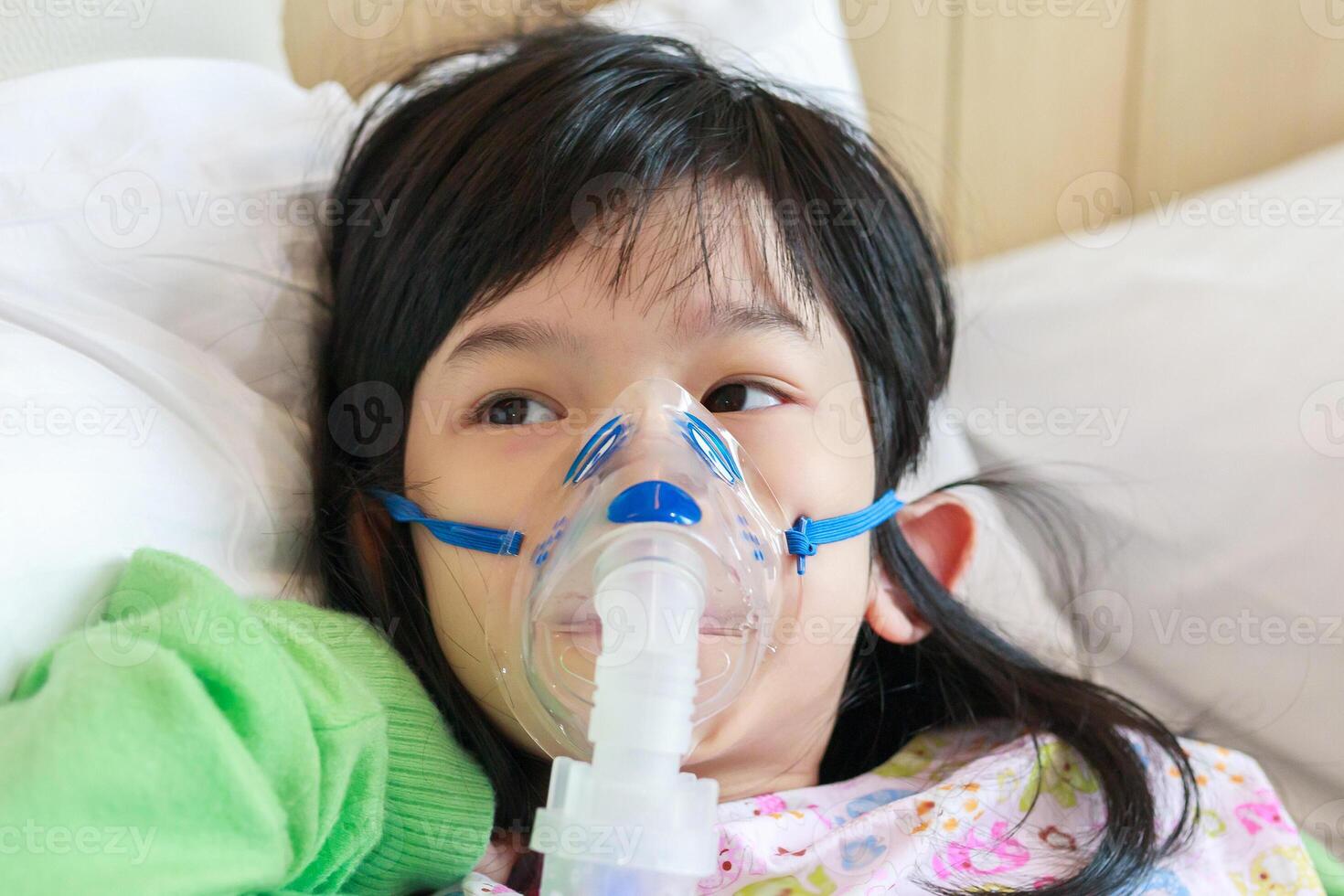 Sick little asian girl inhalation with nebulizer for respiratory treatment photo