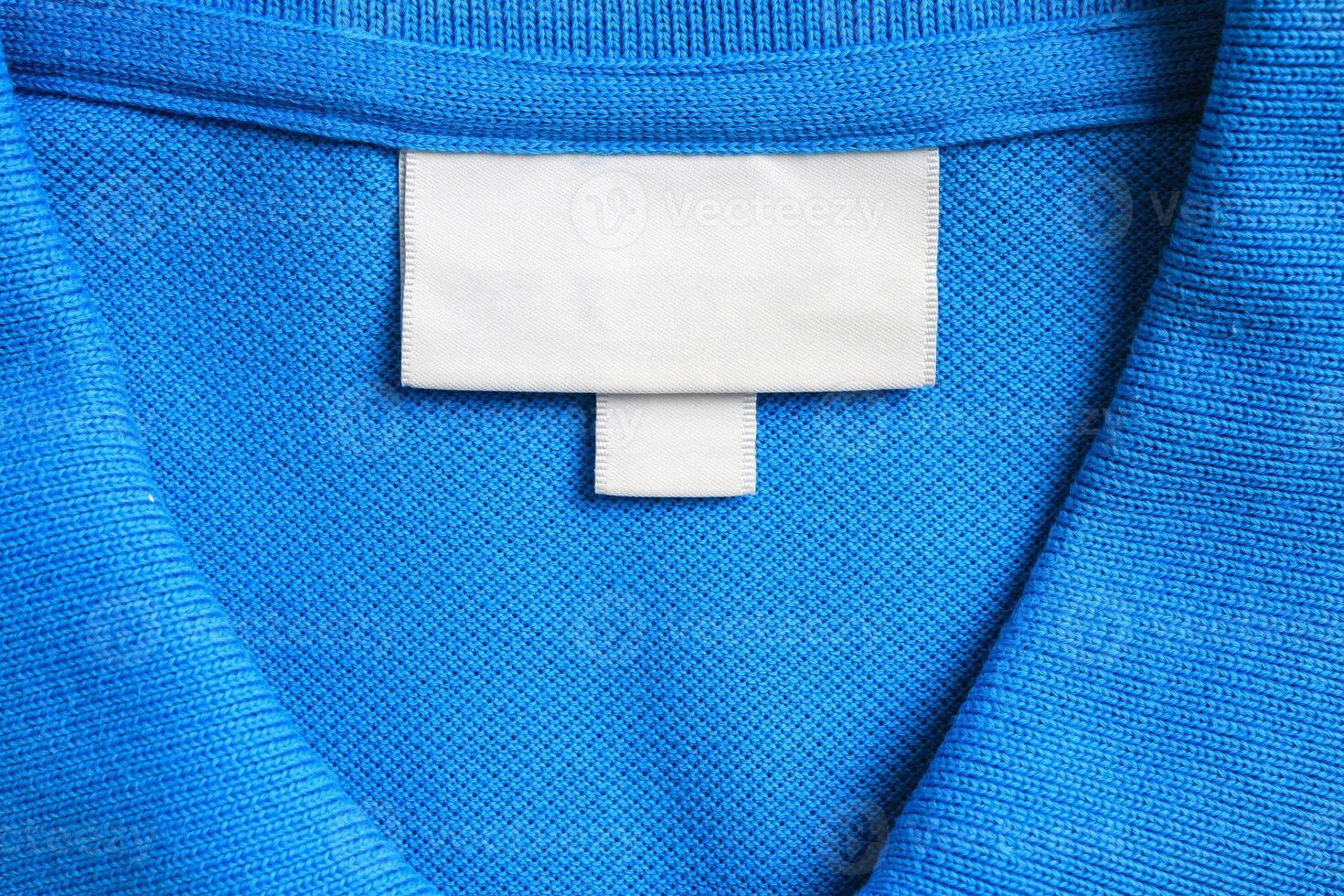Blank white laundry care clothes label on blue shirt fabric texture background photo