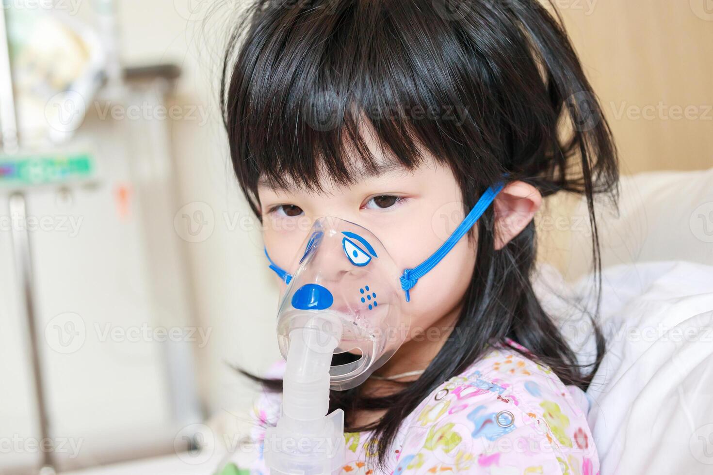 Sick little asian girl inhalation with nebulizer for respiratory treatment photo
