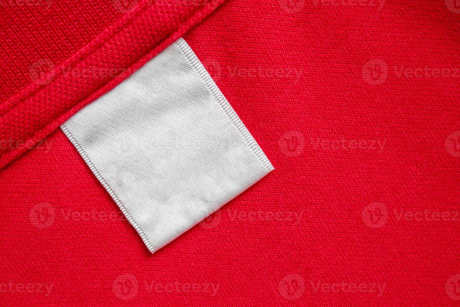 Blank white laundry care clothes label on red shirt fabric texture background photo