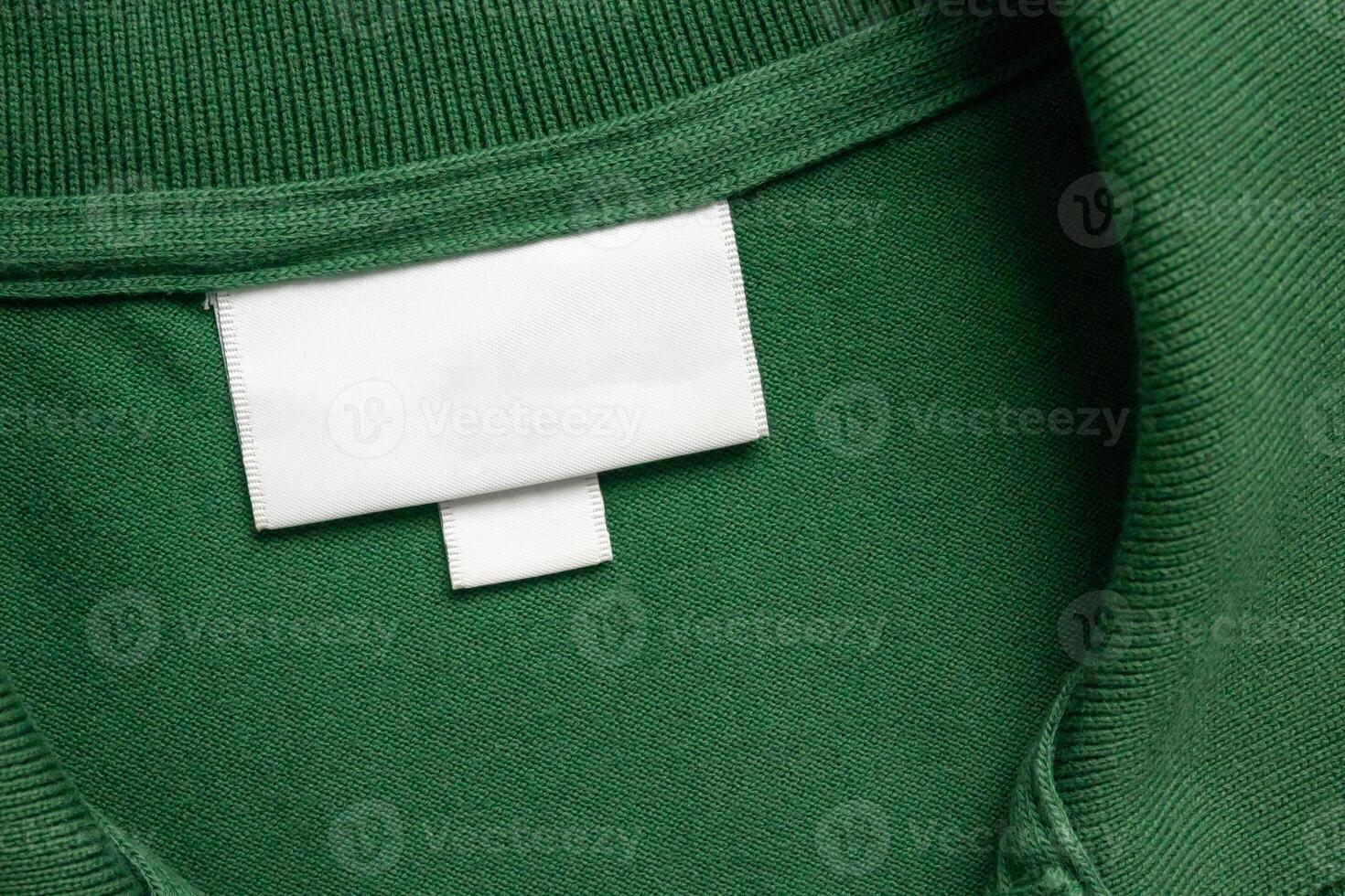 Blank white laundry care clothes label on green shirt fabric texture background photo