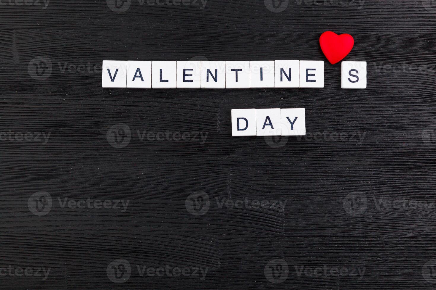 inscription Valentines day on a black wooden background photo