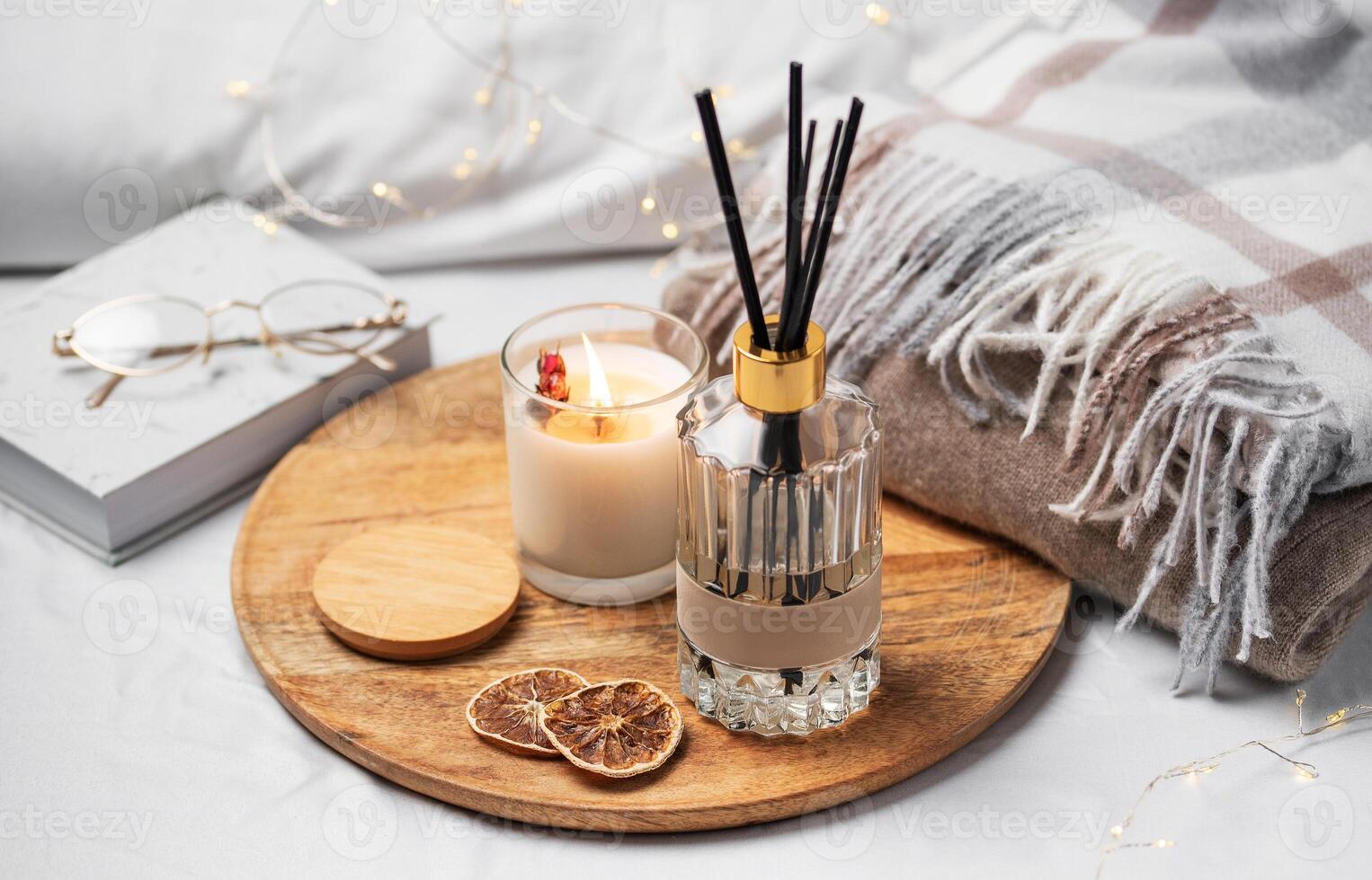 Home fragrance in glass bottle and bamboo sticks with scented candle,  paper book. photo