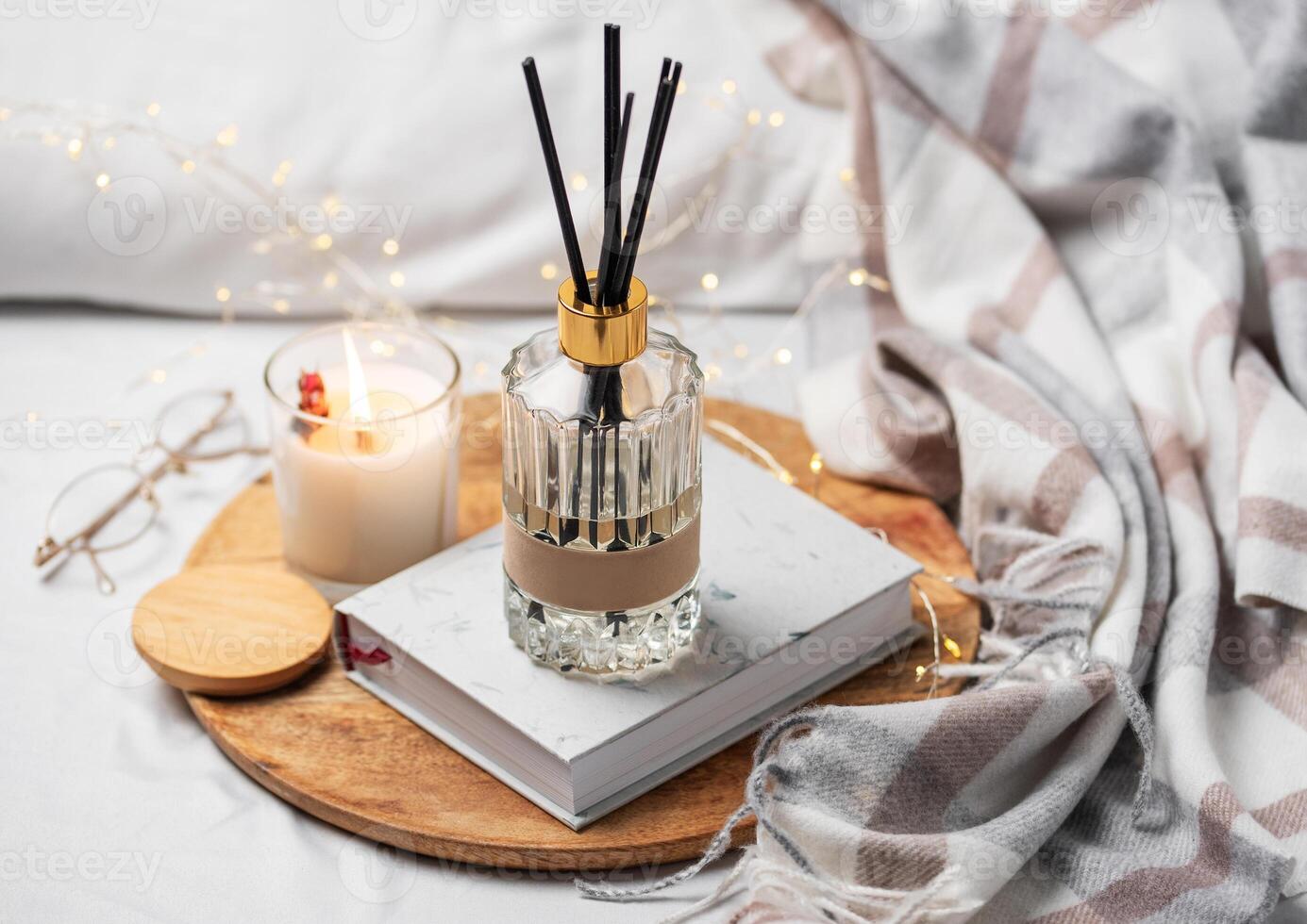 Home fragrance in glass bottle and bamboo sticks with scented candle,  paper book. photo