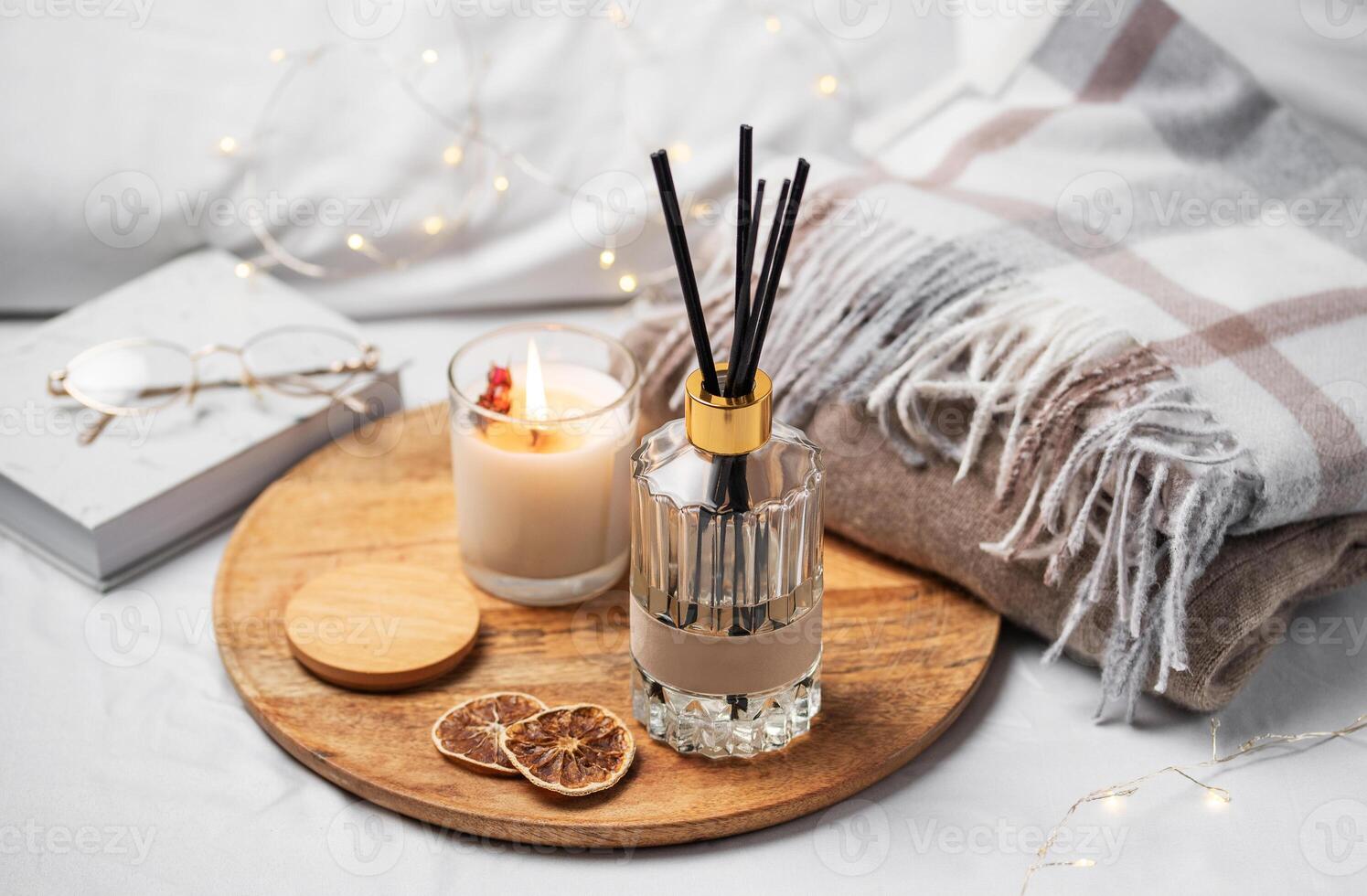 hogar fragancia en vaso botella y bambú palos con perfumado vela, papel libro. foto