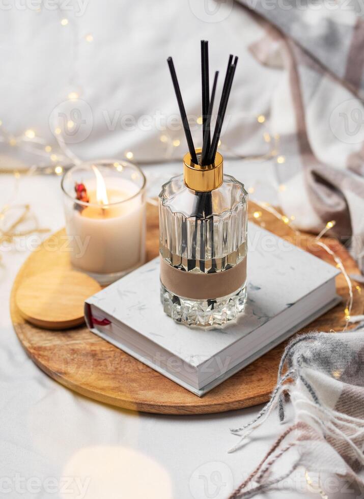 hogar fragancia en vaso botella y bambú palos con perfumado vela, papel libro. foto