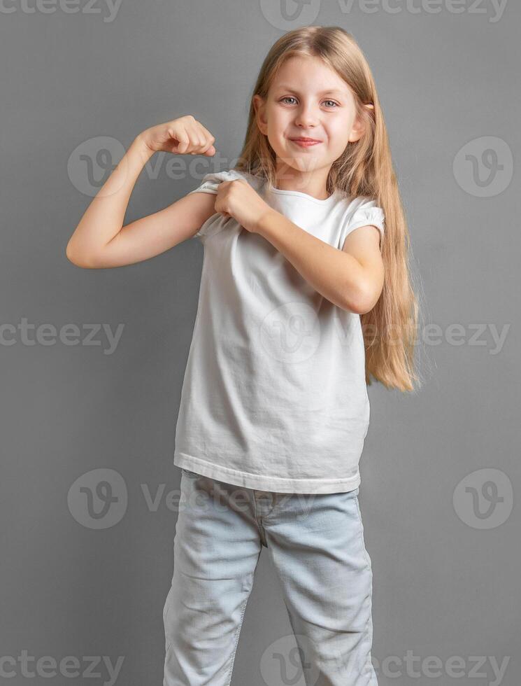 A little girl jokingly shows off her biceps. photo