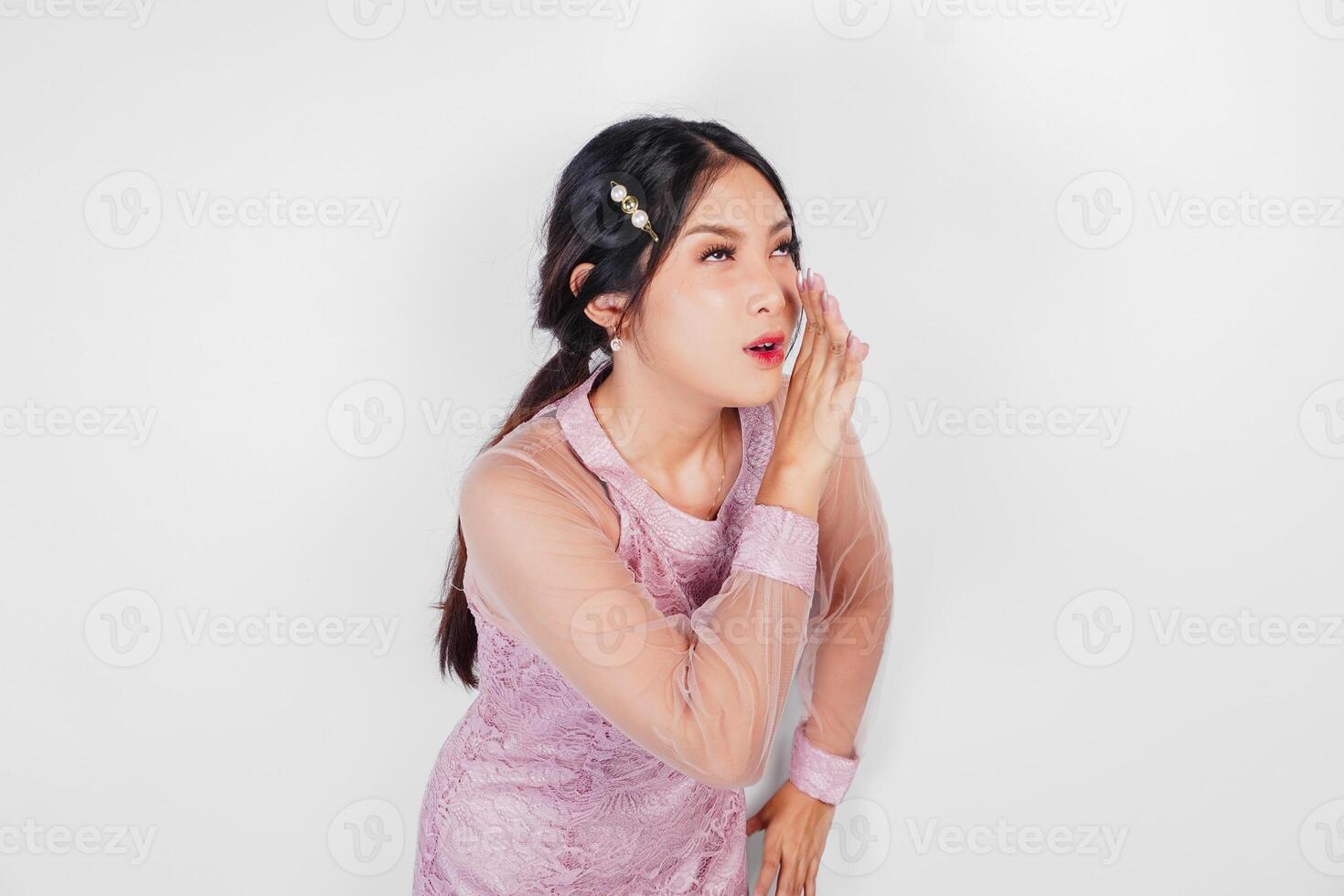 A young beautiful Asian woman is shouting and screaming loud with a hand on her mouth, isolated by white background. photo