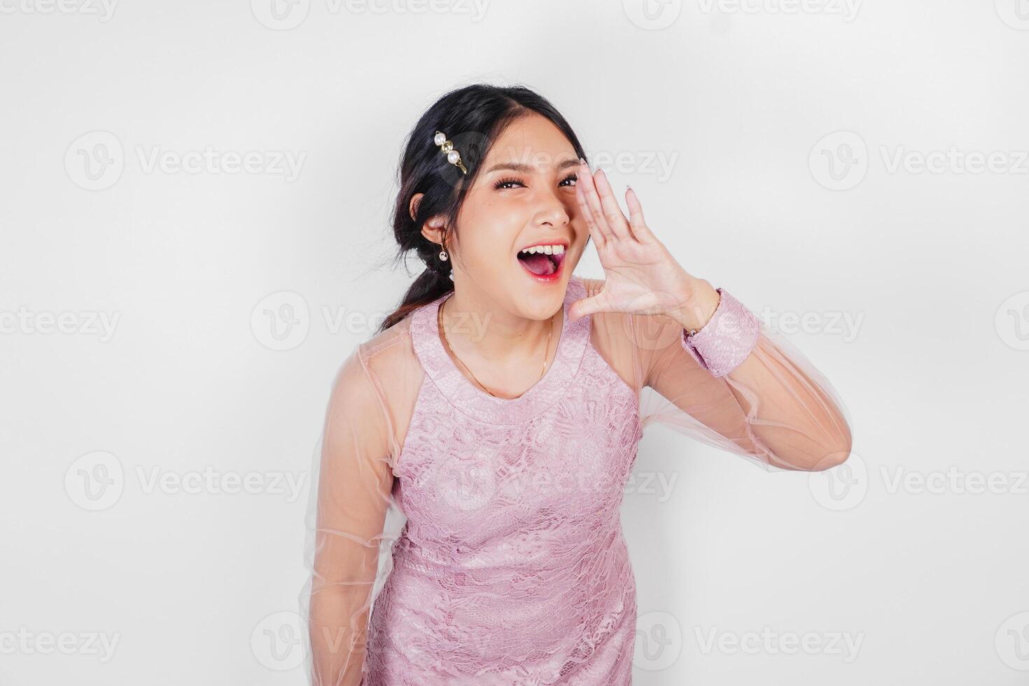 A young beautiful Asian woman is shouting and screaming loud with a hand on her mouth, isolated by white background. photo