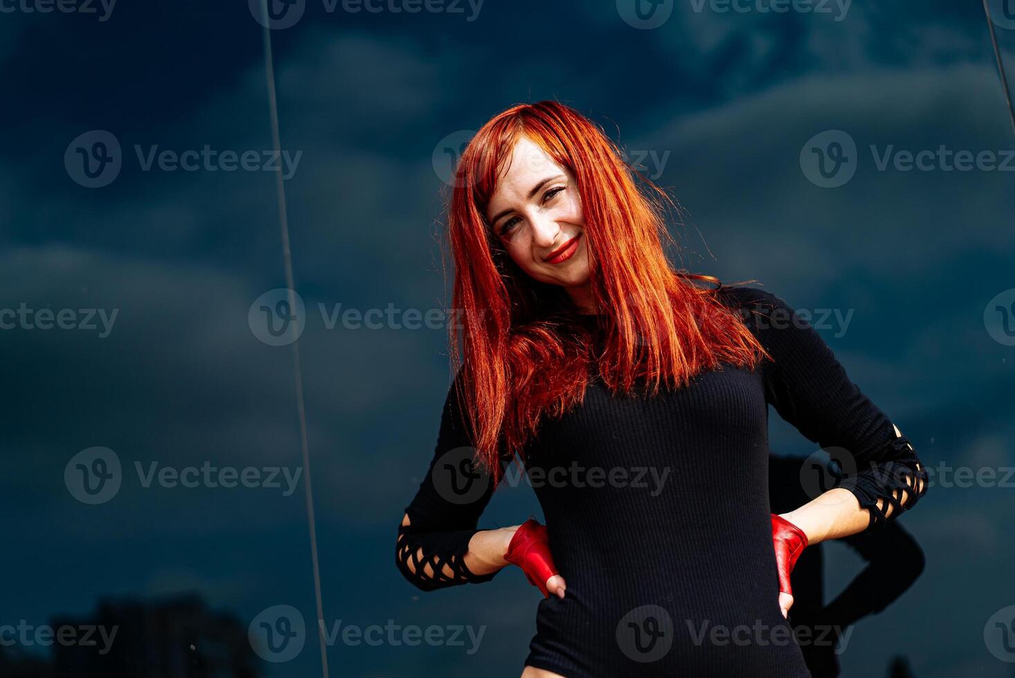 Woman With Red Hair in Black Dress Standing. A woman with red hair standing confidently wearing a black dress. photo