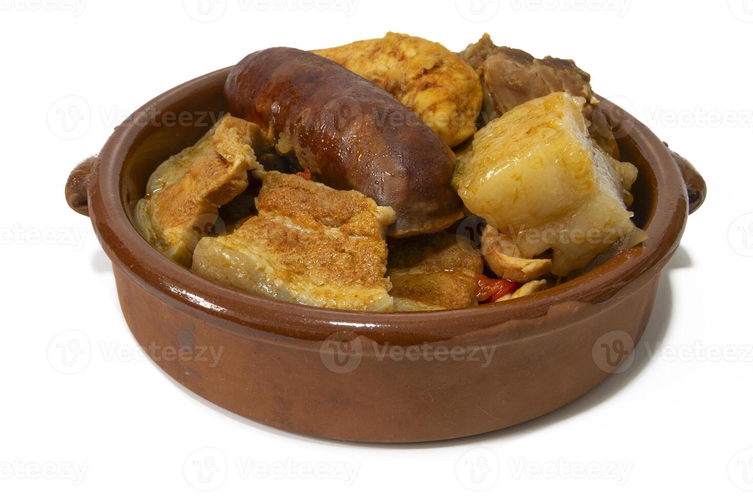 un arcilla cuenco con pringa, chorizo, tocino, tocino, pollo, lomo, y un garbanzo guiso, aislado en un blanco antecedentes. Español comida concepto. foto