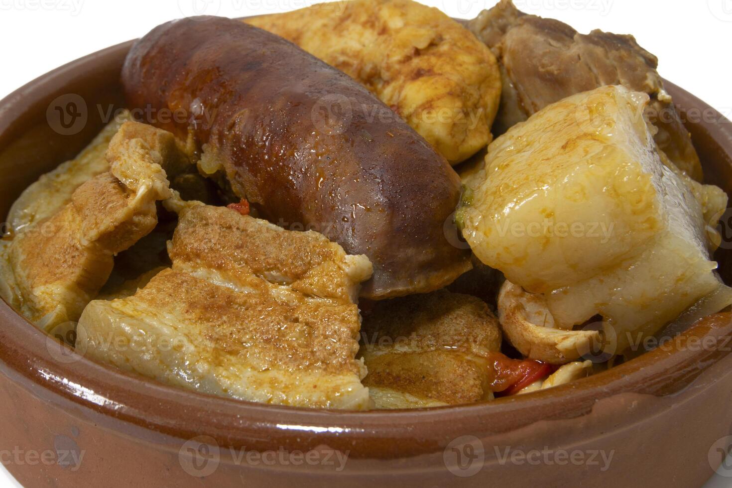 A clay bowl with pringa,mixed meat, chorizo, bacon, chicken, pork loin, from a chickpea stew, isolated on a white background. Spanish food concept. photo