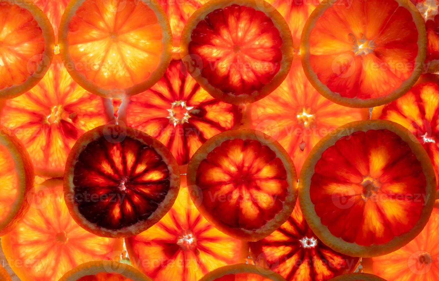 Red oranges fruit background. Sliced juicy orange. Food. Summer concept. Close-up on the light. Translucent photo