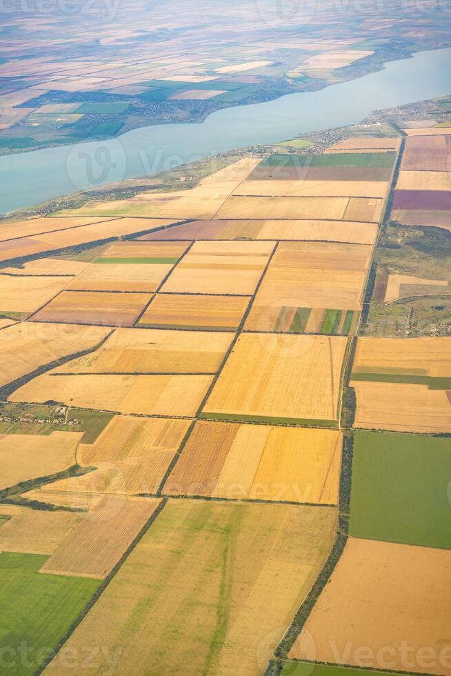 Land view through the airplane window. Fields, roads, rivers from a bird's eye view. Porthole. Look out the window of a flying plane. Top view of the ground photo