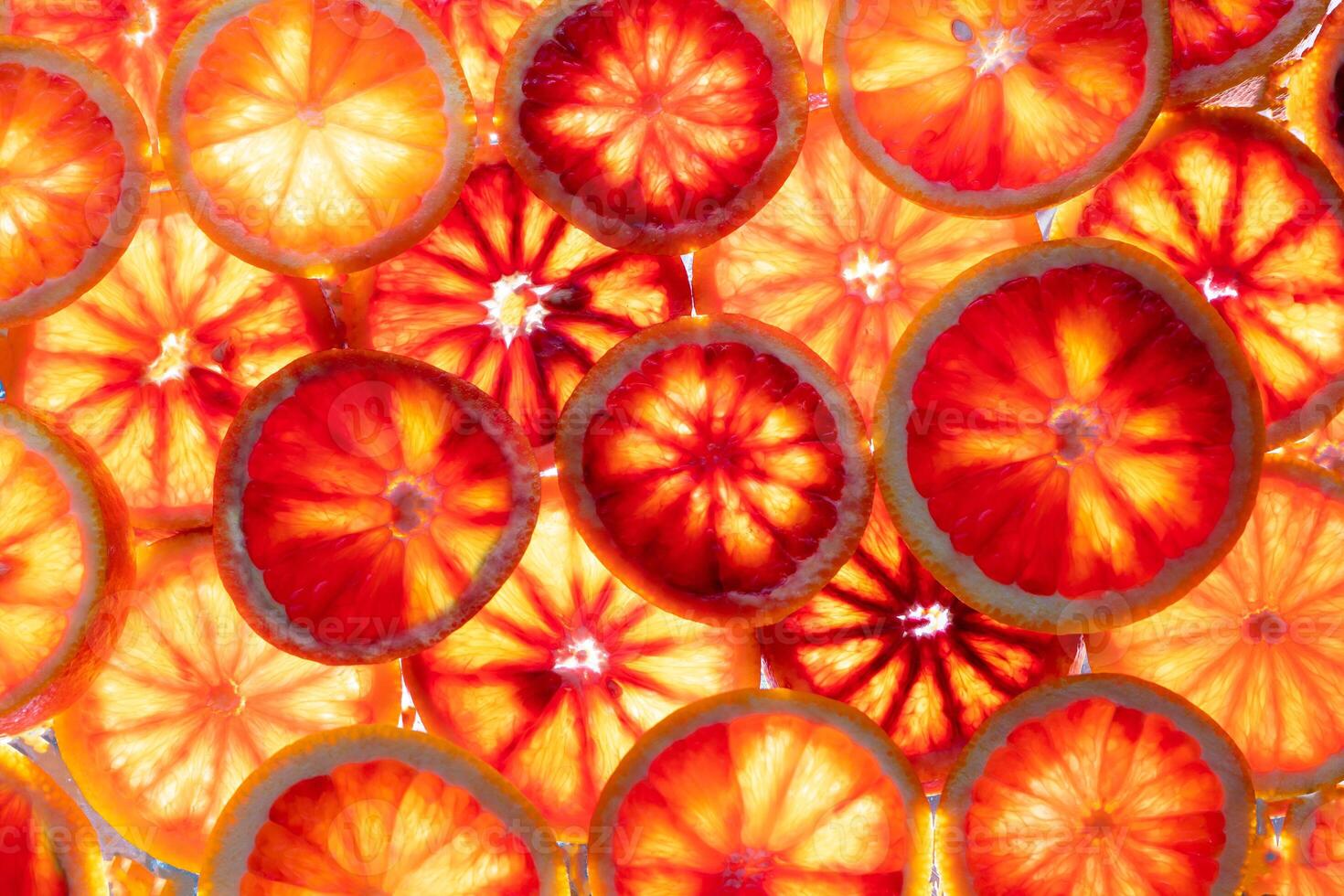 Red oranges fruit background. Sliced juicy orange. Food. Summer concept. Close-up on the light. Translucent photo