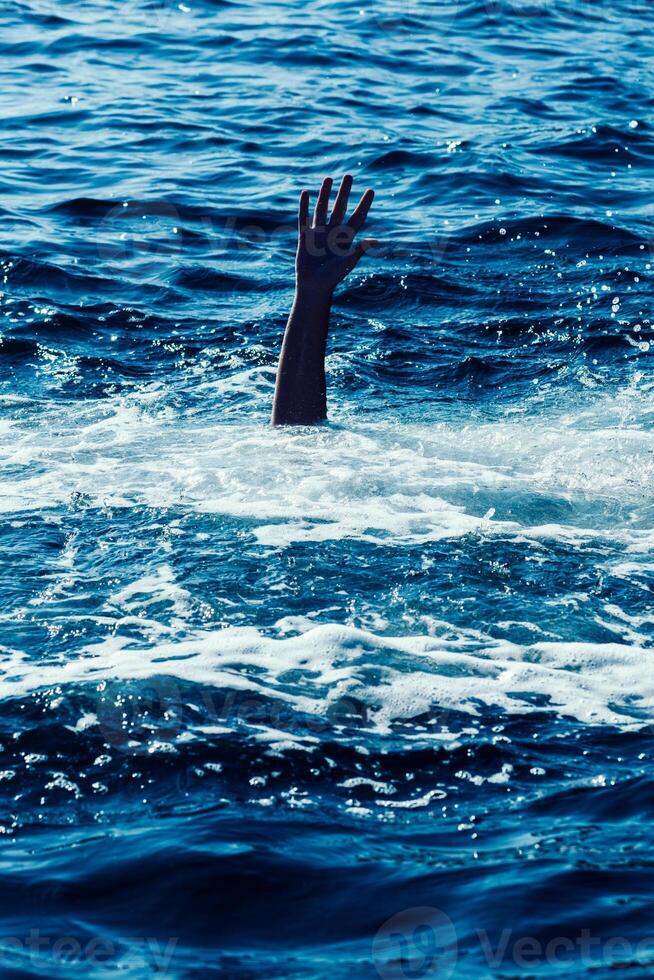 Drowning man in sea asking for help with raised arms photo