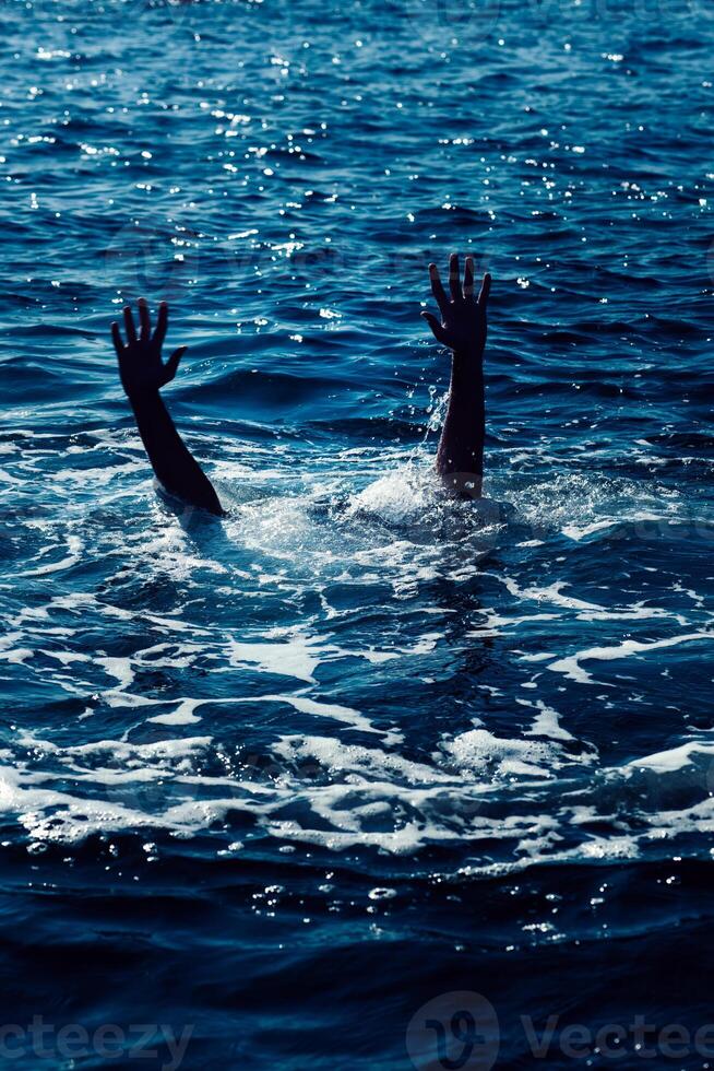 Drowning man in sea asking for help with raised arms photo