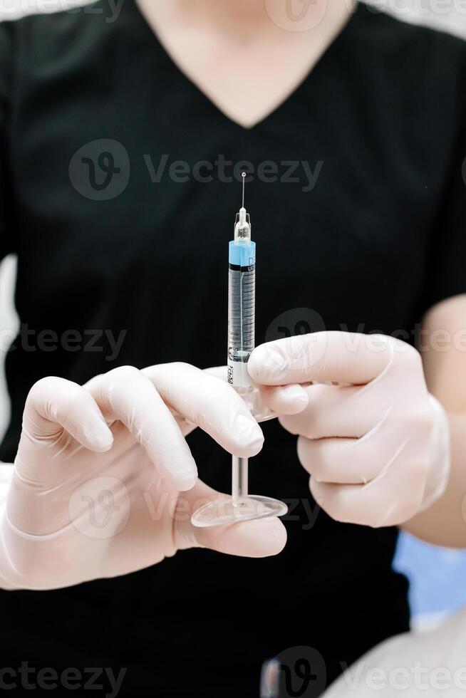 Hand holding a syringe, the syringe is filled with clear liquid. Injection procedure. Lip augmentation, close-up. Advertising concept for facial care photo